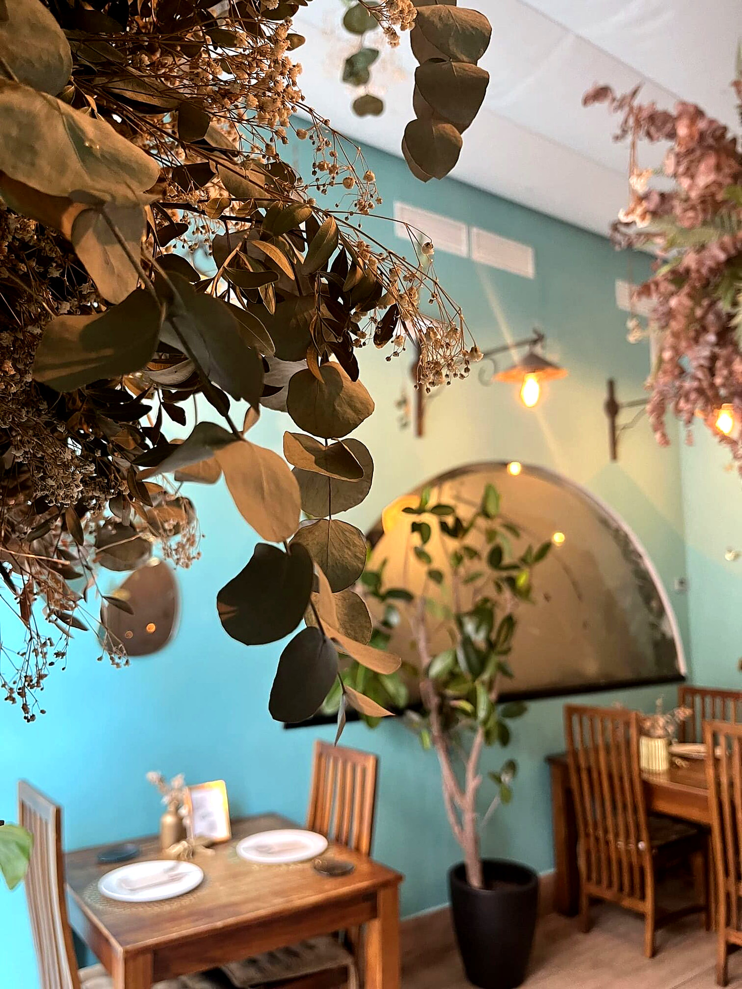 Comedor de El Laurel, con paredes turquesa, flores secas y mesas de madera